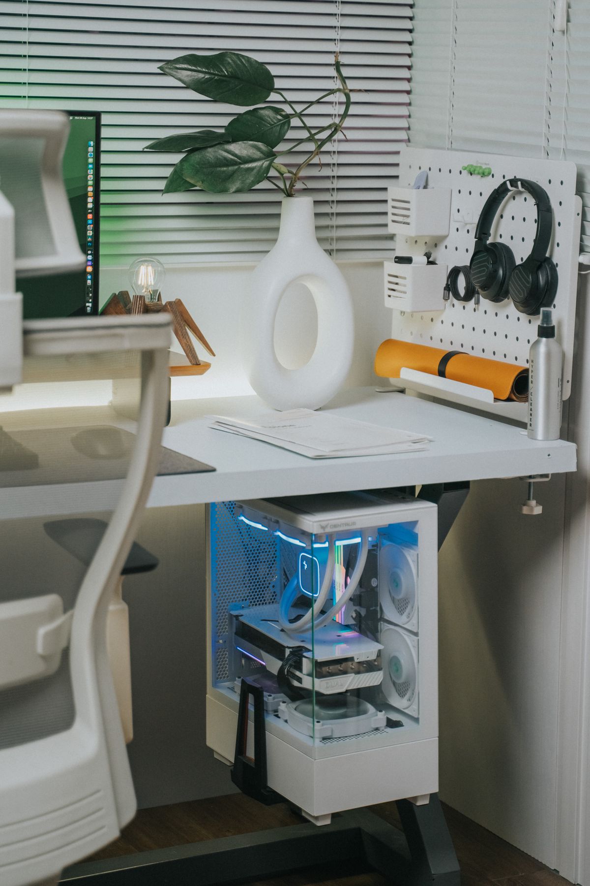 Pracovní stůl s monitorem a bílou počítačovou sestavou pod deskou