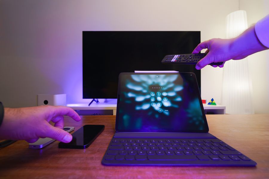 Televizor, tablet a ruce s dálkovým ovladačem